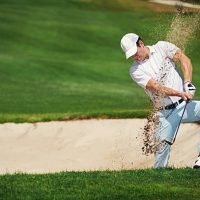 Golfer đang gõ cát khỏi giày khi rời bunker - hành động nhỏ mang ý nghĩa lớn