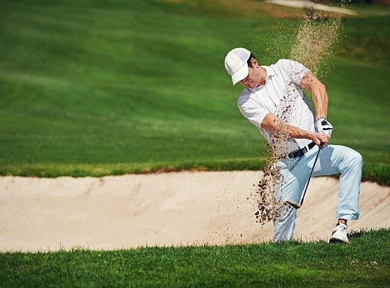 Golfer đang gõ cát khỏi giày khi rời bunker - hành động nhỏ mang ý nghĩa lớn
